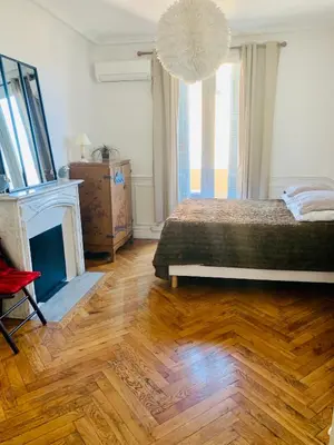 a bedroom with a bed and a fireplace and a chandelier at Appartment Le Charme du Bourgeois in Nice