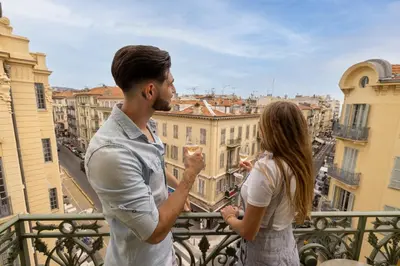 a man and a woman standing on a balcony looking at a city at The Jay Hotel by HappyCulture in Nice