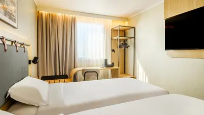 a hotel room with two beds and a desk at Campanile PRIME - Nice Airport in Nice