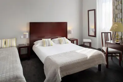 a hotel room with a large bed and a desk at Hôtel Relais Acropolis in Nice