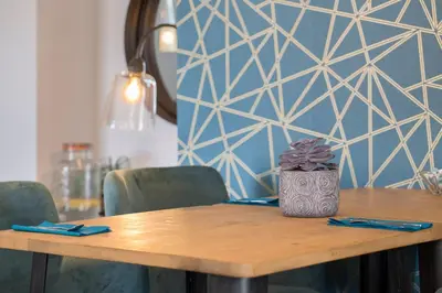 a wooden table with green chairs and a blue wall at Hôtel Relais Acropolis in Nice