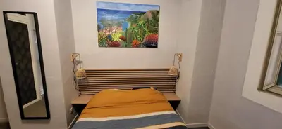 a bed in a room with a painting on the wall at Au Coeur du vieux Nice in Nice