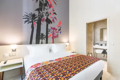 a bedroom with a large bed with palm trees on the wall at Palais Saleya Boutique Hôtel in Nice