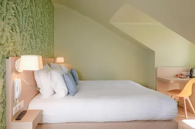a bedroom with a bed with white sheets and a lamp at Hôtel Du Centre, un hôtel AMMI in Nice