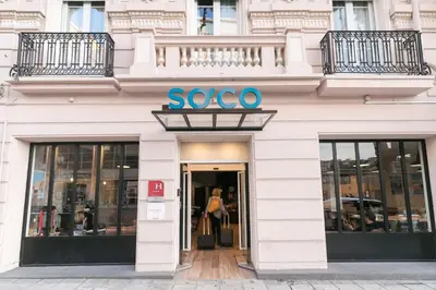 a woman walking into a store with a sign on it at Hotel So’Co by Happyculture in Nice