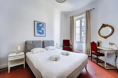 a bedroom with a bed and a table and a mirror at L'Écrin Blanc Niçois - Welkeys in Nice