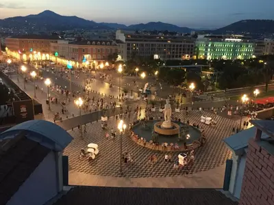 a plaza with a fountain in a city at night at Apartment on Place Massena in Nice