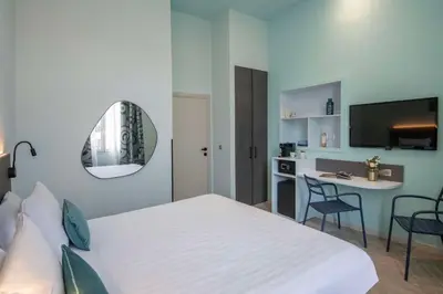 a bedroom with a bed and a table and a mirror at Best Western Alba in Nice