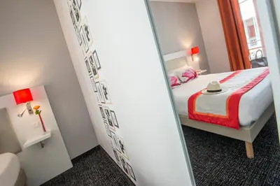 a small room with a bed and a mirror at Hôtel Amaryllis in Nice