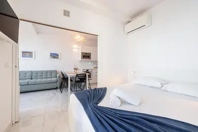 a white bedroom with a bed and a table at Sea view - 2 Bdr Promenade des Anglais in Nice