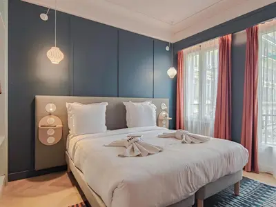 a bedroom with a large bed with blue walls at Hotel Aparthotel AMMI Nice Lafayette in Nice