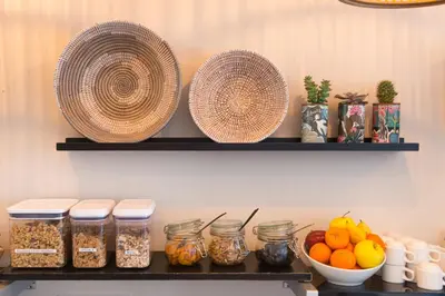 a shelf with two baskets and jars of food at Hotel Select in Beaulieu-sur-Mer