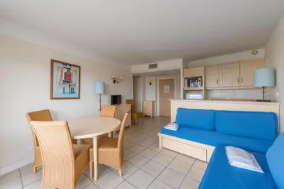 a living room with a blue couch and a table at Residence Heliotel Marine - maeva Home in Saint-Laurent-du-Var