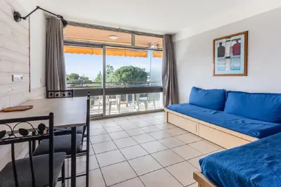 a living room with a blue couch and a desk at Residence Heliotel Marine - maeva Home in Saint-Laurent-du-Var