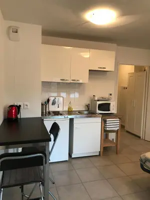 a kitchen with white appliances and a table and chairs at beau studio in Nice