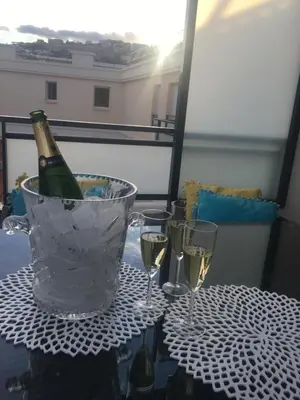 a bottle of champagne in a bucket on a table with glasses at Riviera Terrasse - parking gratuit in Nice