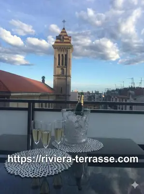 a bottle of wine and glasses on a table on a balcony at Riviera Terrasse - parking gratuit in Nice