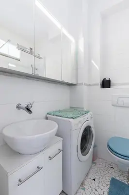 a white bathroom with a washing machine and a sink at Promenade des anglais Vue mer in Nice