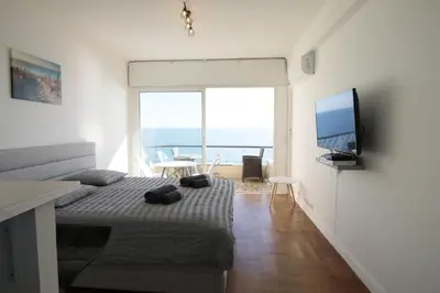 a bedroom with a bed with a television and a balcony at Promenade des anglais Vue mer in Nice