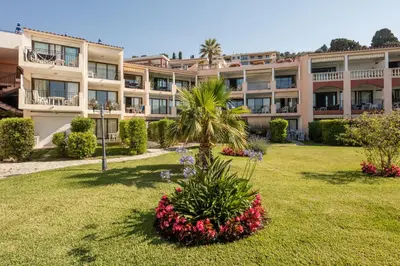 an apartment building with a palm tree in a yard at Résidence Pierre & Vacances l'Ange Gardien in Villefranche-sur-Mer