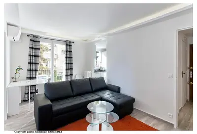 a living room with a black couch and a table at Parc Anahit in Nice