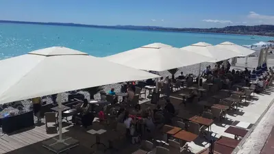 a group of people sitting under white umbrellas on a beach at Lovely house in Cagnes-sur-Mer