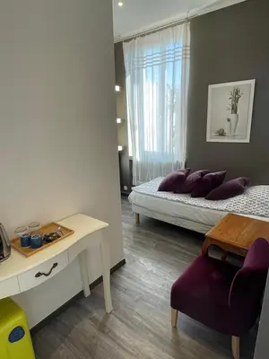 a bedroom with a bed with purple pillows and a table at Hôtel La Villa Patricia - Charme et Tradition in Villefranche-sur-Mer