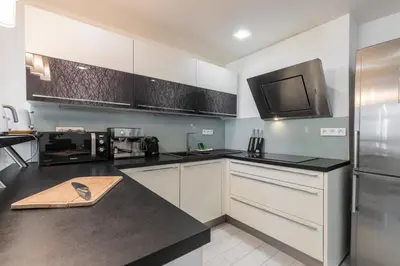 a kitchen with white cabinets and a stainless steel refrigerator at Amazing 3 Bdrs and Garden Place du Pin Parking ! in Nice