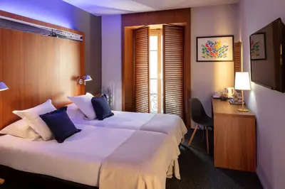 a hotel room with two beds and a desk at Hotel Beau Rivage in Nice