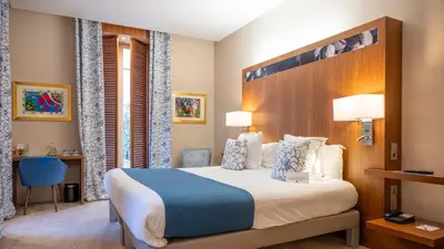 a hotel room with a large bed and a desk at Hotel Beau Rivage in Nice