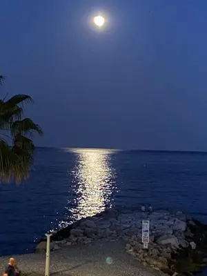 a full moon over the ocean at night at O Phare du Cros in Cagnes-sur-Mer