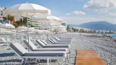 a row of lounge chairs and umbrellas on a beach at Aoustin in Nice