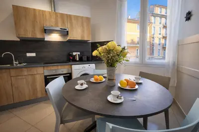 a kitchen with a table with a vase of oranges on it at Promenade Appartements les Lions in Nice