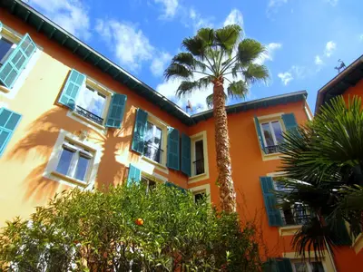 an orange building with a palm tree in front of it at Maison Durante in Nice