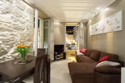 a living room with a table and chairs and a stone wall at Apartment with parking in Nice near the harbor in Nice