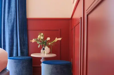 a red room with two blue stools and a table with flowers at Hôtel Petit Palais in Nice