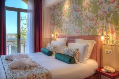 a bedroom with a bed with pillows and a window at Hôtel Petit Palais in Nice