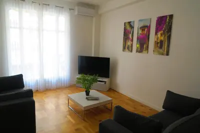 a living room with a couch and a tv and a table at Carré d’Or Appt 4 Pièces moderne et spacieux in Nice