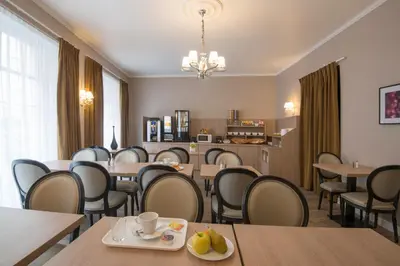 a dining room with tables and chairs and a chandelier at Hotel Paganini in Nice