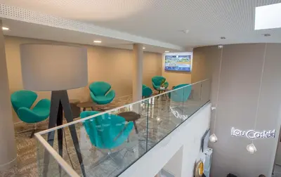 a lobby with green chairs and a glass railing at Hotel Lou Castelet in Carros