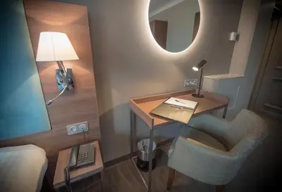 a room with a desk and a chair and a mirror at Hotel Lou Castelet in Carros