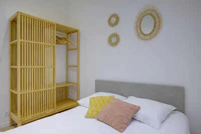 a bedroom with a white bed with a wooden cabinet at Maison Bianchi - Raspail in Nice