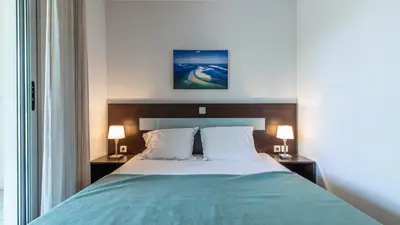 a bed in a hotel room with two lamps on tables at Vacancéole - Résidence Le Crystal in Cagnes-sur-Mer