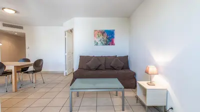 a living room with a couch and a table at Vacancéole - Résidence Le Crystal in Cagnes-sur-Mer