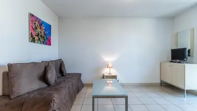 a living room with a couch and a table at Vacancéole - Résidence Le Crystal in Cagnes-sur-Mer