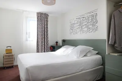 a bedroom with a white bed and a window at Hotel Restaurant Isidore by Soniho in Nice