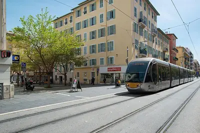 a train traveling down a city street with buildings at Republique Garibaldi in Nice