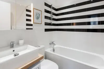 a bathroom with a white tub and a toilet and a sink at Le Studio Graphite Welkeys in Nice