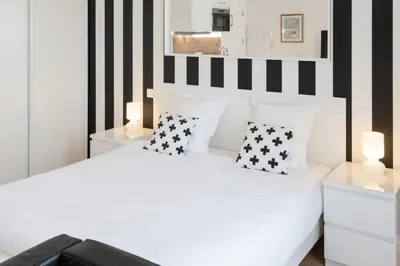 a bedroom with a white bed with black and white stripes at Le Studio Graphite Welkeys in Nice