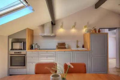 a kitchen with white cabinets and a wooden table at Maison Lamartine - Nice in Nice